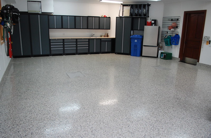 Garage showing installed cabinets, slatwall, and coated floor